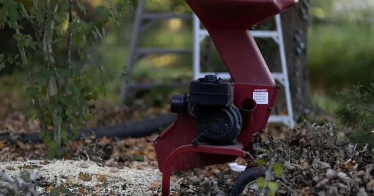 Small yard wood chipper standing among fallen leaves and fresh wood chips