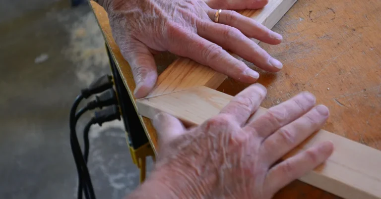 Woodworker's hands fitting two mitered picture-frame moldings together at a 45-degree corner joint