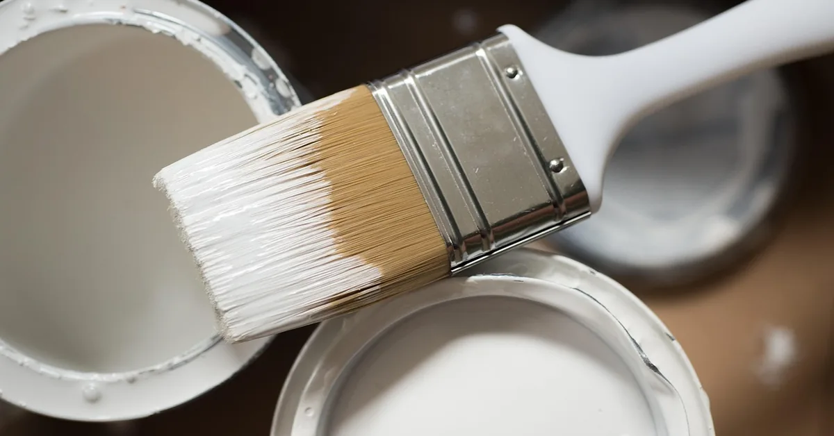 two open cans of paint with a stir stick, one labeled for indoor use and one for outdoor use