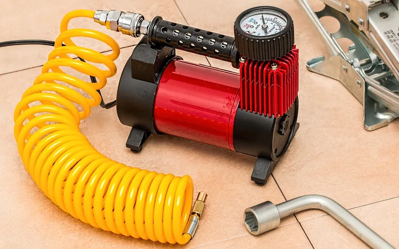 small portable air compressor with coiled air hose and a lug wrench