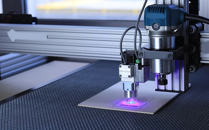 Laser engraver burning a branching pattern into wood, a genuinely safe alternative to high-voltage Lichtenberg burning