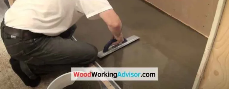 Worker troweling a sloped mortar bed for a shower pan over a plywood floor