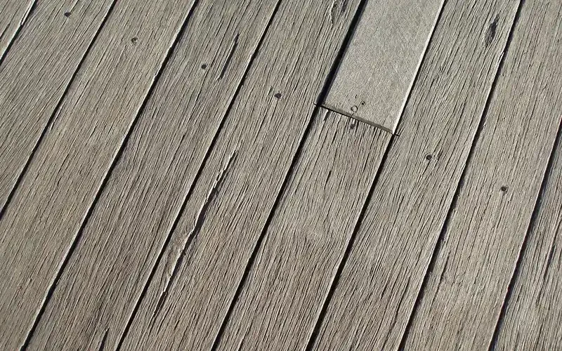 weathered gray wooden deck boards with cracks and wear