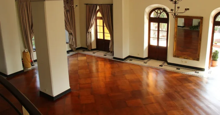 Glossy hardwood parquet floor reflecting window light in a large room