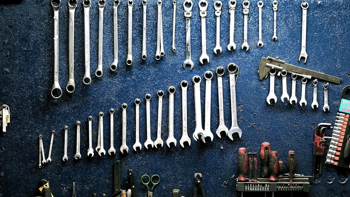 Set of wrenches hanging on a blue workshop pegboard