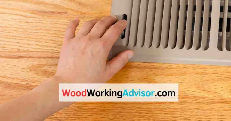 Hand checking a floor register vent set into a hardwood floor