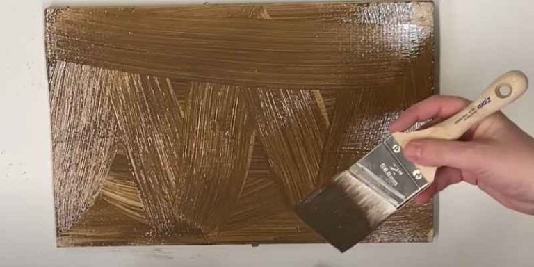 dry-brushing a bronze metallic glaze onto a wood panel with visible cross-hatched brush texture
