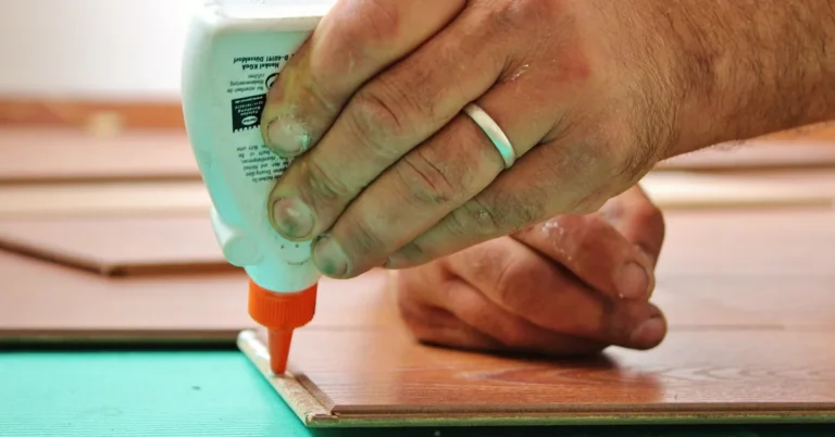 Carpenter applying glue to the edge of a wood board before clamping the joint