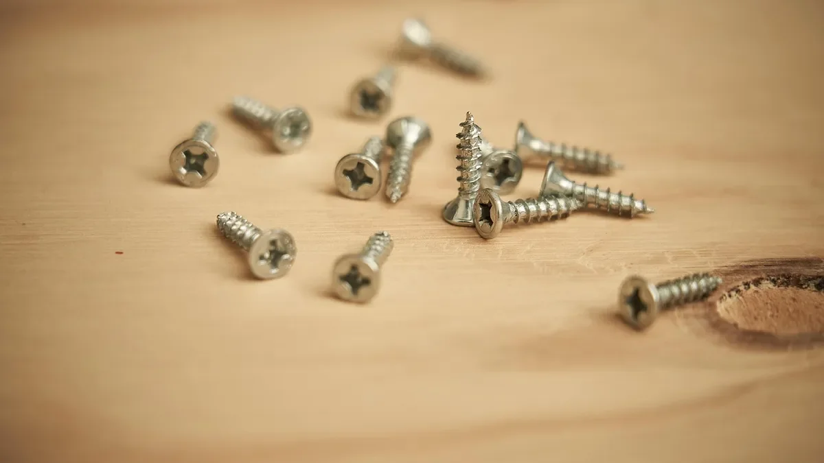 Loose wood screws scattered on a light wood board