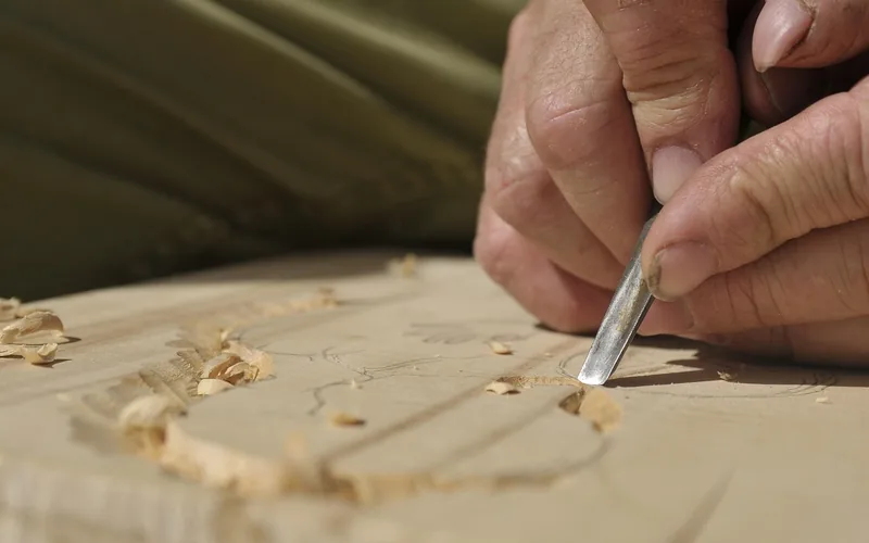 Carpenter chiseling into a hardwood block to check grain and density Carpenter chiseling into a hardwood block to check grain and density