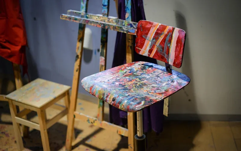 Wooden chair seat covered in many layers of paint in a studio