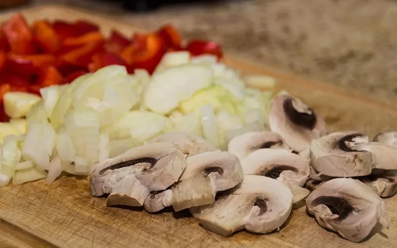 Chopped onion, bell pepper and mushrooms on a wooden cutting surface Chopped onion, bell pepper and mushrooms on a wooden cutting surface
