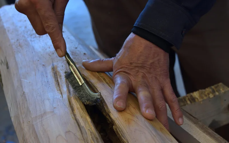 Cleaning raw wood with a wire brush before applying stain