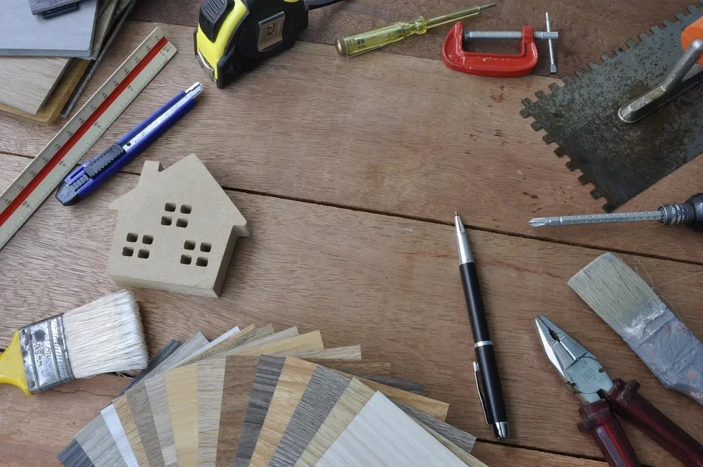 Tape measure, utility knife, clamp and flooring plank swatches laid out on a wood surface