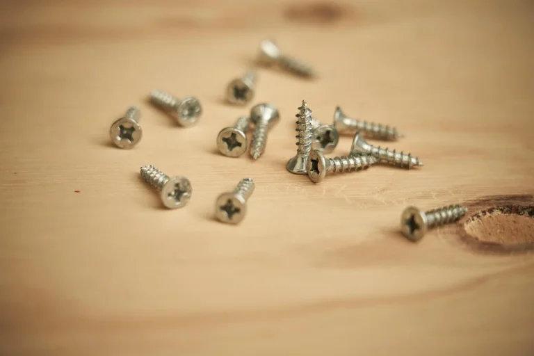 Loose Phillips-head wood screws scattered on a pine board