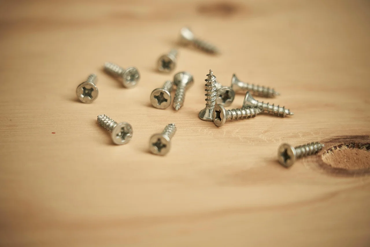 Loose Phillips-head wood screws scattered on a pine board