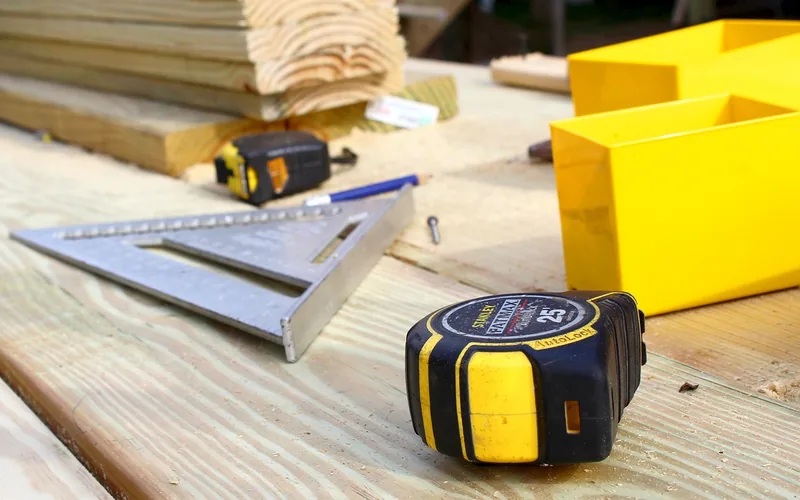 Tape measure and speed square on hardwood flooring planks before installation