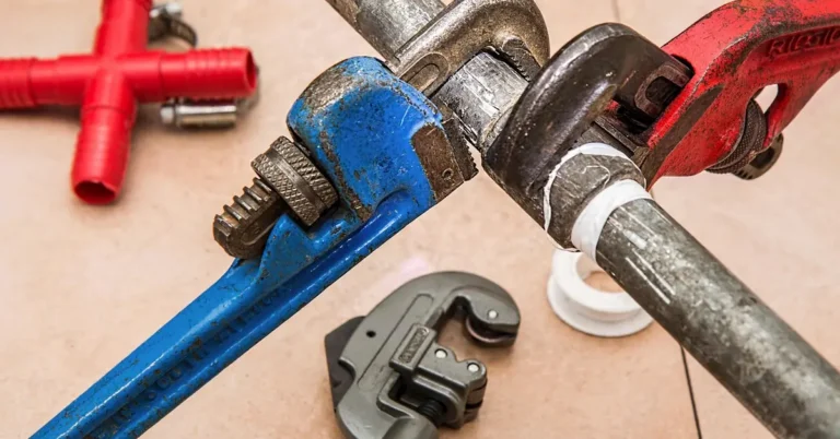 plumber using a wrench on a pipe during a bathroom wall renovation