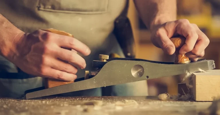 Woodworker's hands smoothing a wooden surface with a hand plane during a repair project
