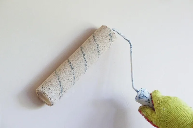 Paint roller applying a fresh coat to an interior wall