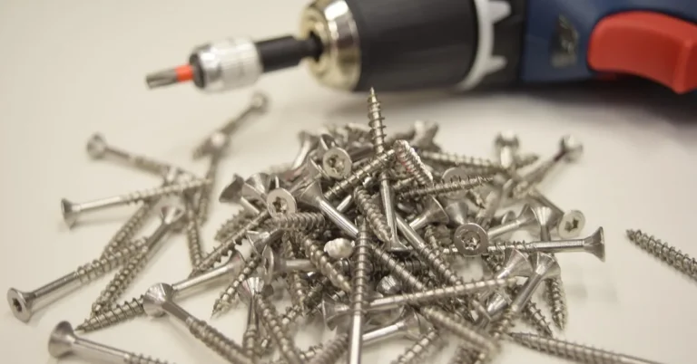 Pile of star-drive stainless screws next to a cordless drill fitted with a driver bit