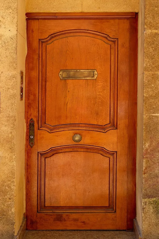 Varnished wooden entry door with brass letter slot set in a stone wall Varnished wooden entry door with brass letter slot set in a stone wall