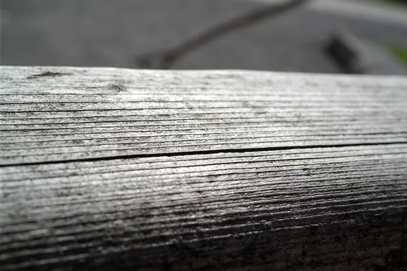 Weathered gray wooden rail with surface grooves and checks