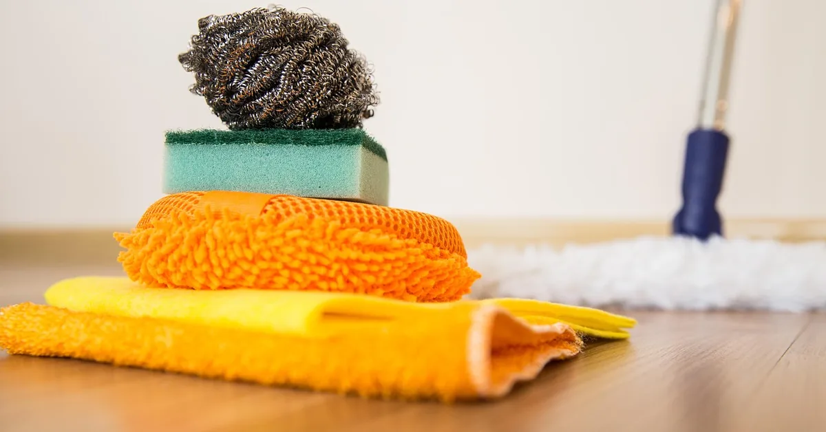 Cleaning cloths, sponge and mop on a wood floor
