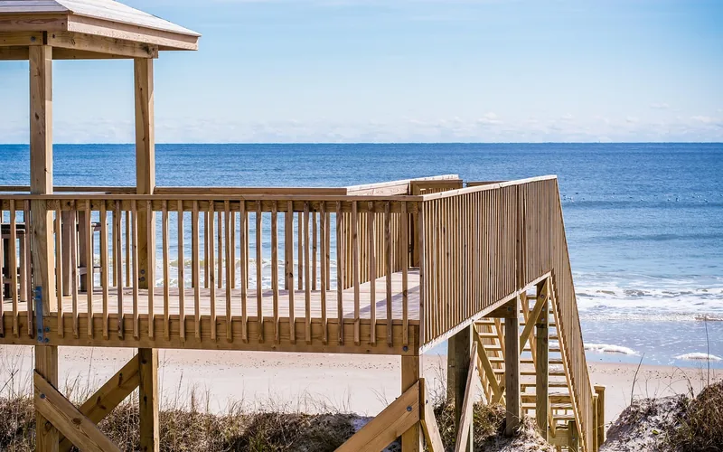 close-up of a natural wood deck railing with evenly spaced vertical balusters and top rail close-up of a natural wood deck railing with evenly spaced vertical balusters and top rail