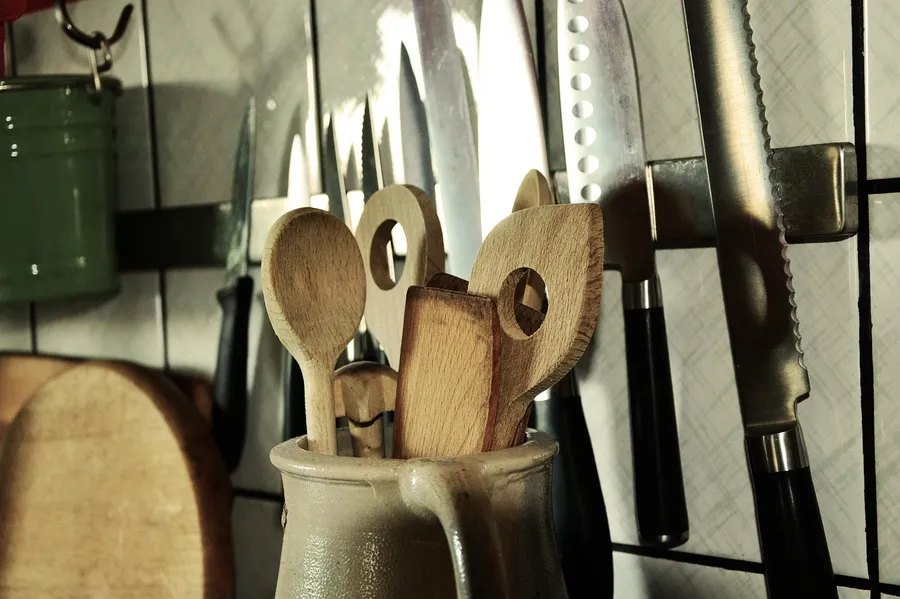 Wooden kitchen utensils stored in a crock beside kitchen knives
