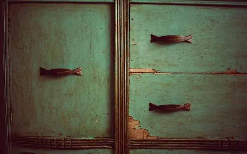 Worn green painted dresser doors with chipped paint and metal handles Worn green painted dresser doors with chipped paint and metal handles