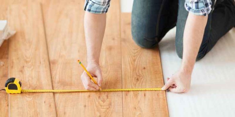 Marking a low spot on a hardwood floor Hands using a tape measure and pencil to mark a low spot on a hardwood floor before leveling