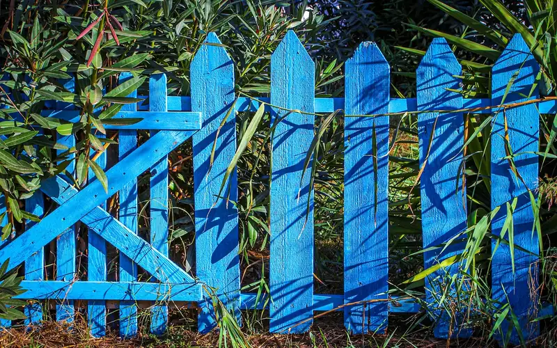 Blue painted picket fence with pickets fastened to horizontal rails Blue painted picket fence with pickets fastened to horizontal rails