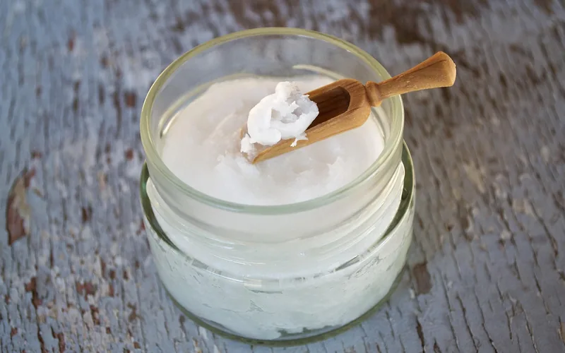 applying food grade mineral oil to a wooden utensil with a wooden spoon applying food grade mineral oil to a wooden utensil with a wooden spoon