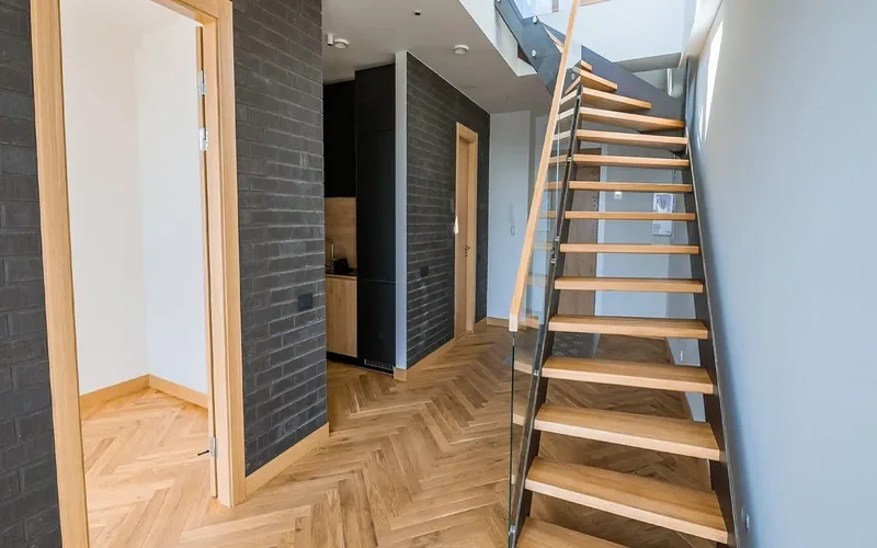 Herringbone oak hardwood floor in a finished interior with oak door trim