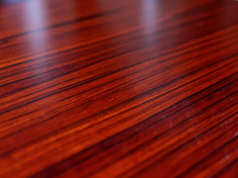 Close-up of polished mahogany wood grain showing the fine straight grain pattern furniture makers value