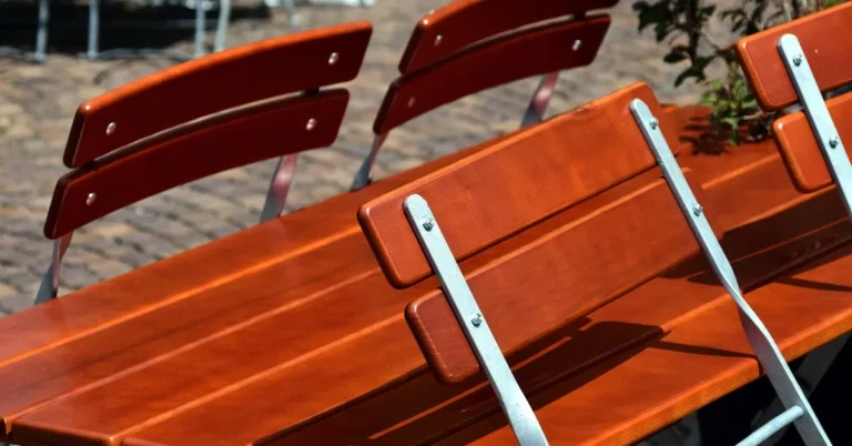Varnished wooden outdoor table and chairs on a paved terrace