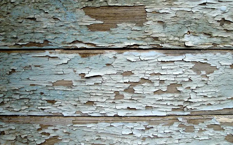 cracked and peeling paint on wood siding exposing bare wood to moisture