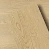 Light oak peel-and-stick flooring sample used to test tone against dark wood paneling