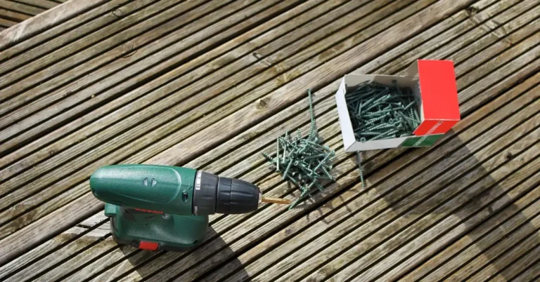 cordless drill and box of deck screws on a wooden deck board