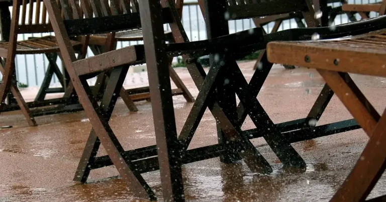 Rain-soaked wooden deck boards and chairs showing why treated wood needs a water repellent