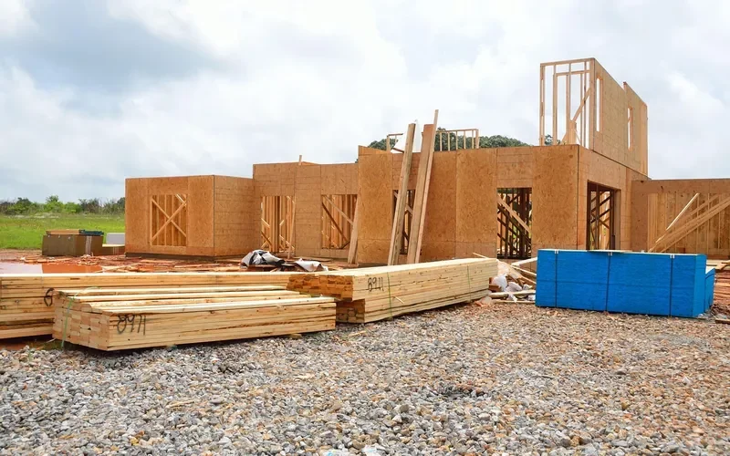 Wall framing and lumber stacks on a new home foundation Wall framing and lumber stacks on a new home foundation