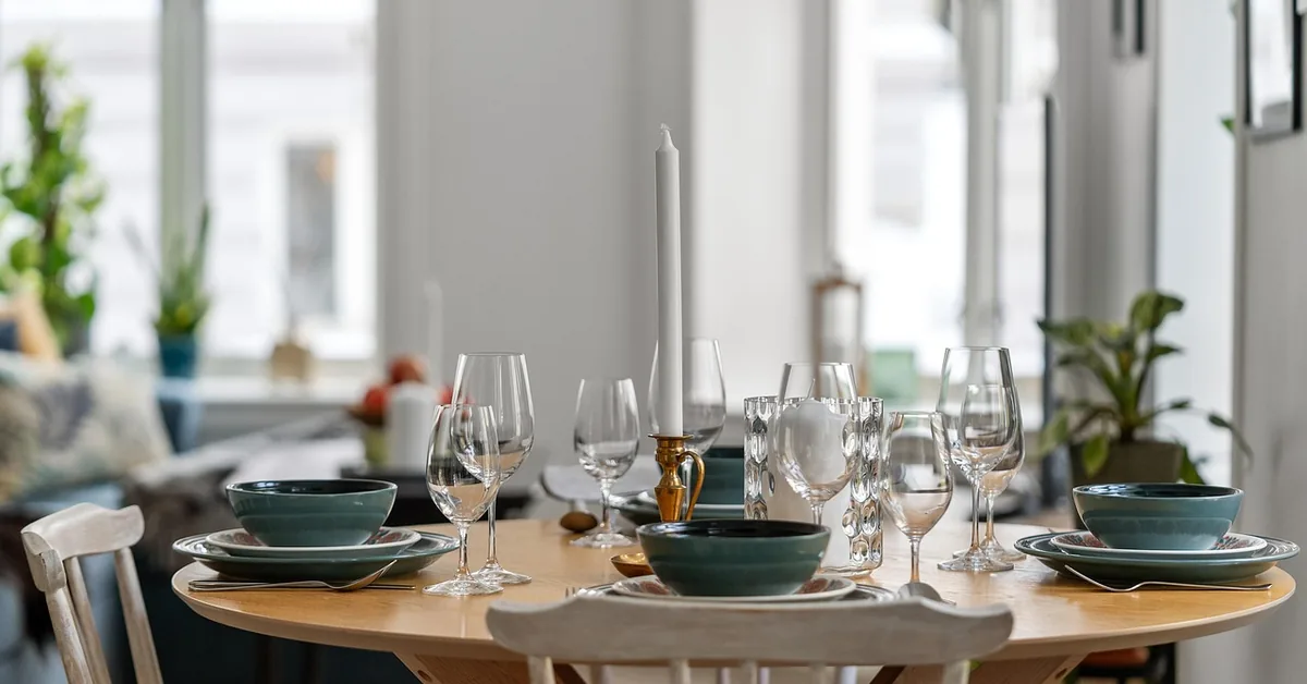 Wood dining table set with glassware and dinnerware, protected surface with a felt-padded chair beside it