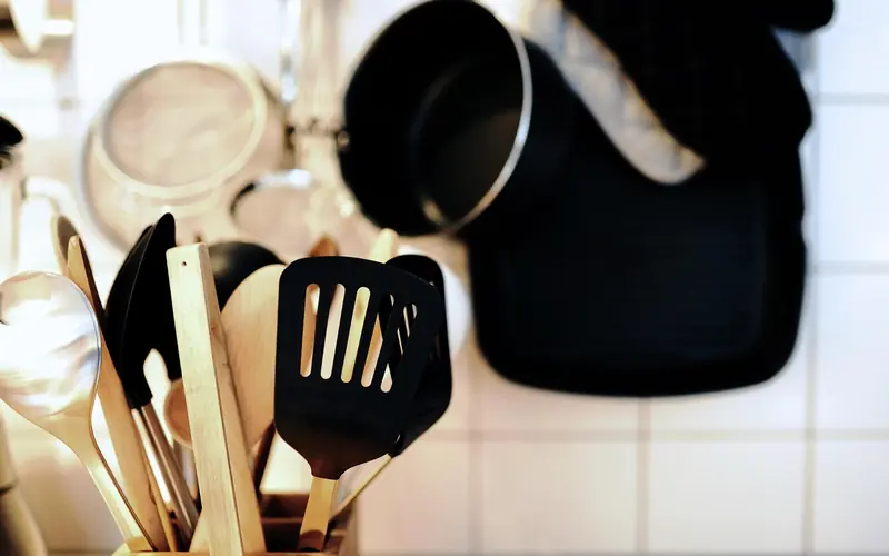wooden spoons and black utensils standing together in a kitchen holder wooden spoons and black utensils standing together in a kitchen holder
