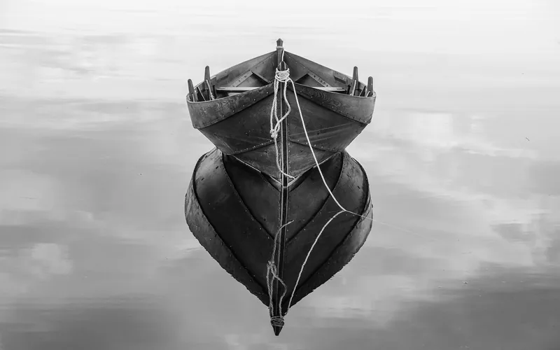 Wooden rowboat moored on calm water with rope tied at the bow