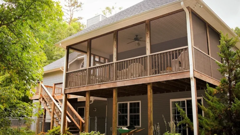 Two-level backyard house with a stained wood deck, railing and stairs