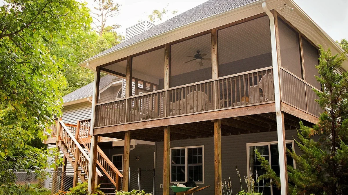 Two-level backyard house with a stained wood deck, railing and stairs