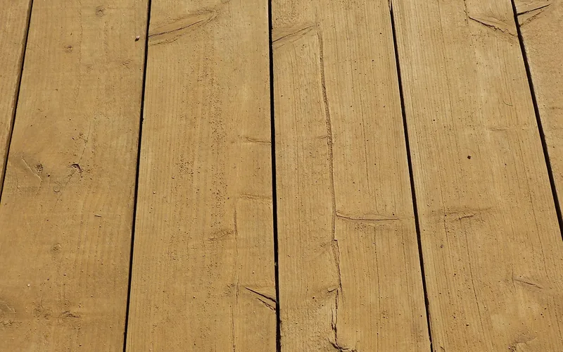 Clean tan wood deck boards with tight gaps and visible grain Clean tan wood deck boards with tight gaps and visible grain