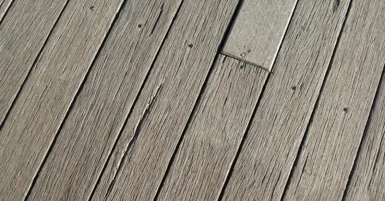 Weathered gray wood deck boards with fasteners, showing outdoor wear