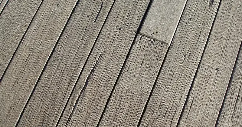 Weathered gray wood deck boards with fasteners, showing outdoor wear